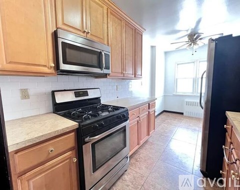 A kitchen with wooden cabinets and a black refrigerator.