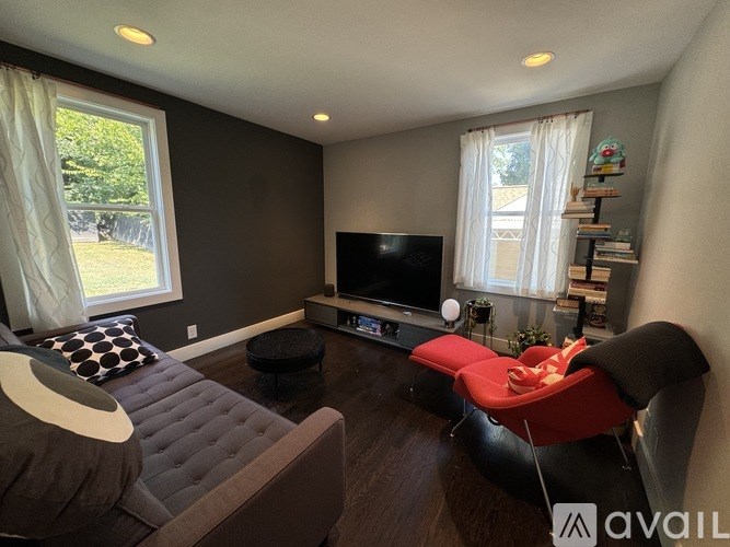 A living room with a grey couch, a red chair, and a television.