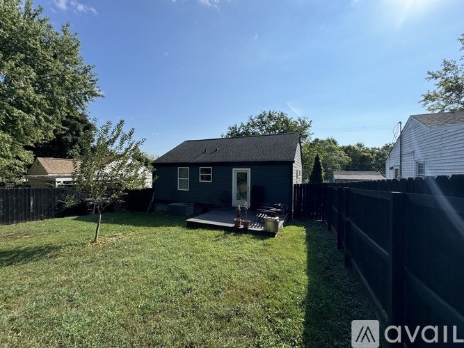 A small house with a black roof and a white fence.