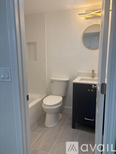 A bathroom with a toilet, sink and mirror.