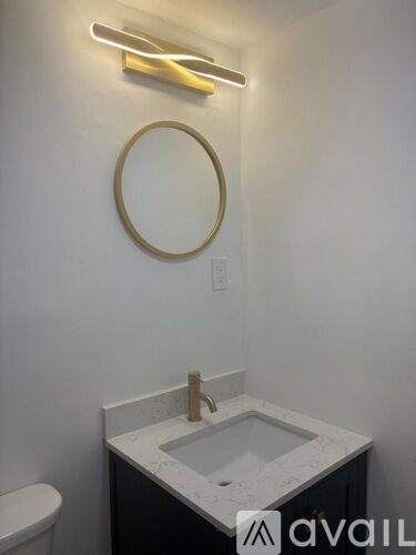 A bathroom with a white sink and a round mirror.