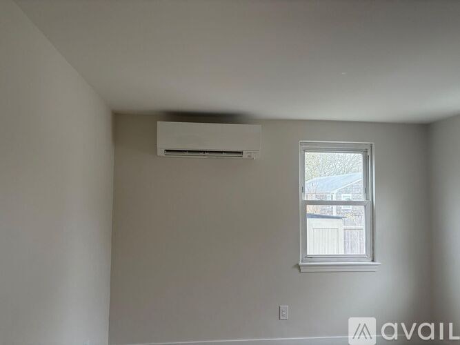 A room with a window and an air conditioner on the ceiling.