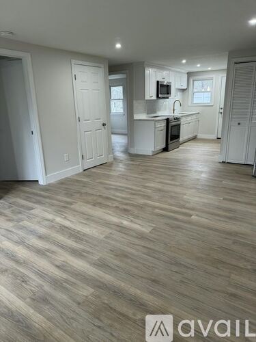 A spacious kitchen with white cabinets and a wooden floor.