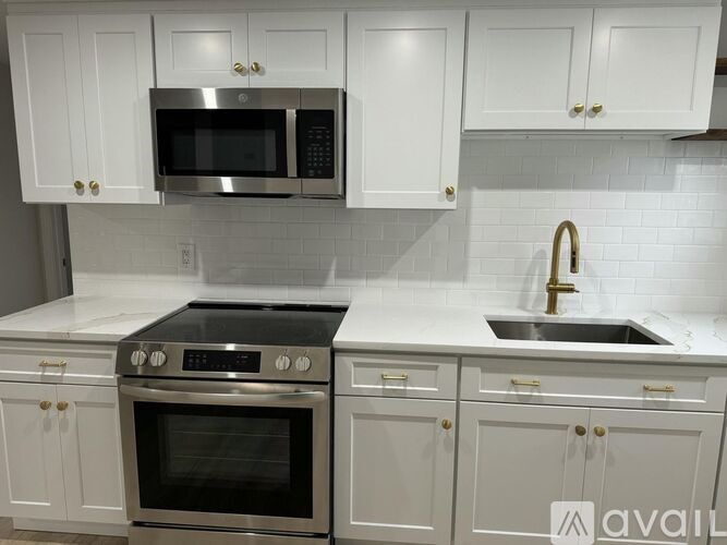 A kitchen with white cabinets and a stainless steel oven and microwave.