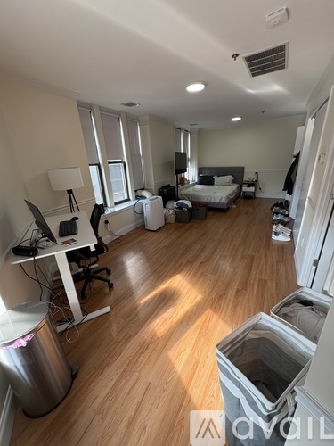 A room with a bed, desk, and trash can.