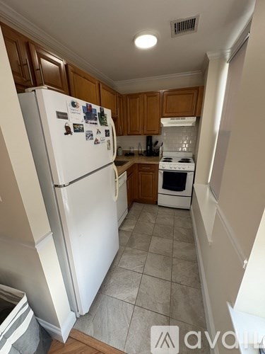 A kitchen with a white fridge and wooden cabinets.