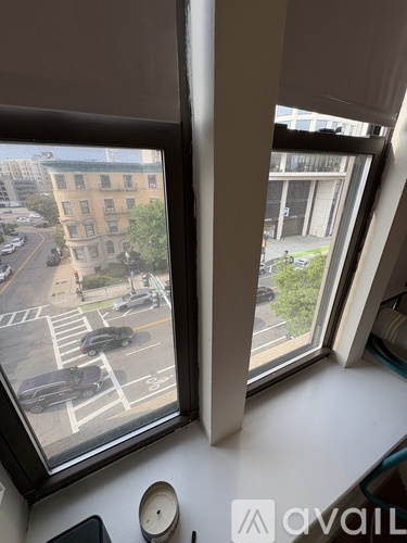 Two windows looking out at a street with cars and buildings.
