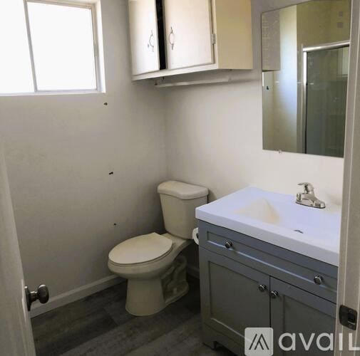 A bathroom with a toilet, sink, and mirror.