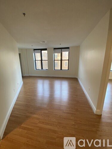 A room with wooden floors and two windows.