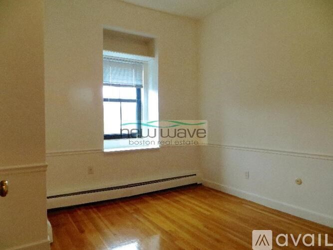 A room with wooden floors and a window with blinds.