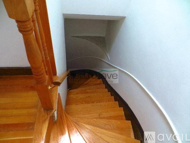 A wooden staircase with a white wall on the side.