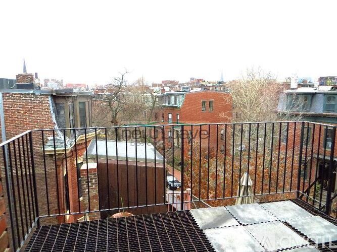 A balcony with a metal railing and a brick wall.