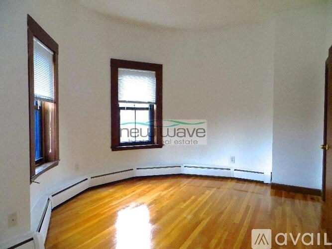 A room with wooden floors and two windows is available for rent.