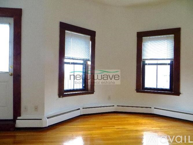 A room with wooden floors and two windows with blinds.