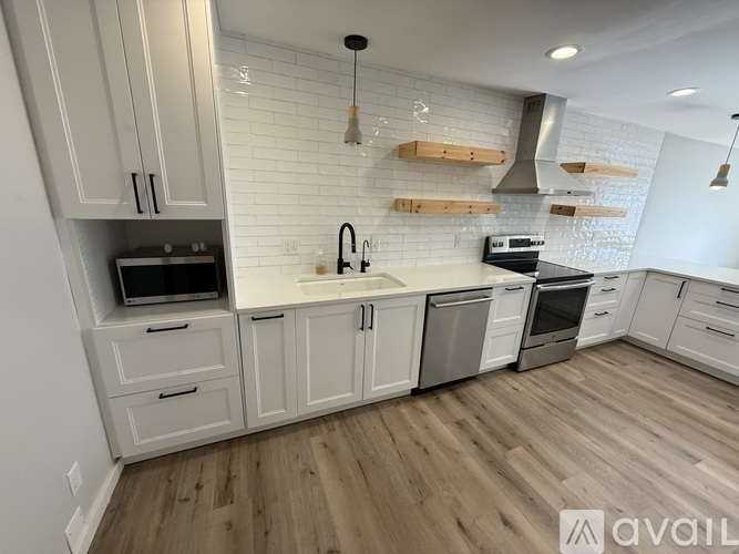 A kitchen with white cabinets and a wooden floor.