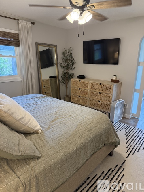 A bedroom with a bed, a dresser, and a ceiling fan.