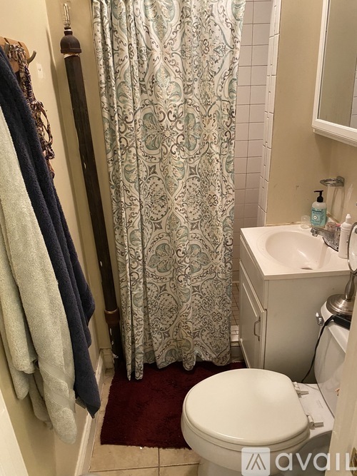A bathroom with a white toilet, a shower curtain, and a towel rack.