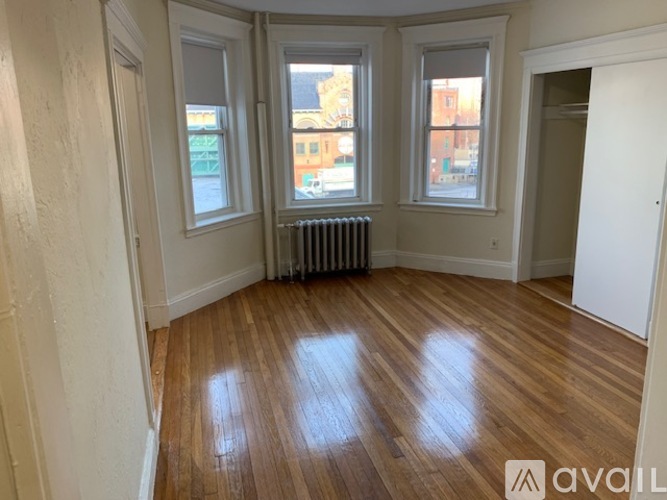 A room with wooden floors and three windows.