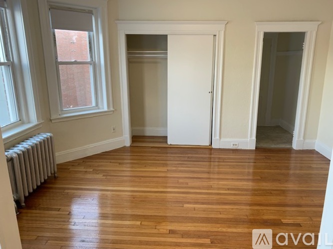 A room with wooden floors and a window with a radiator beneath it.