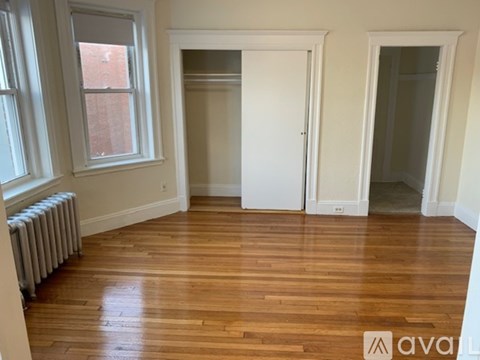 A room with wooden floors and a window with a radiator beneath it.