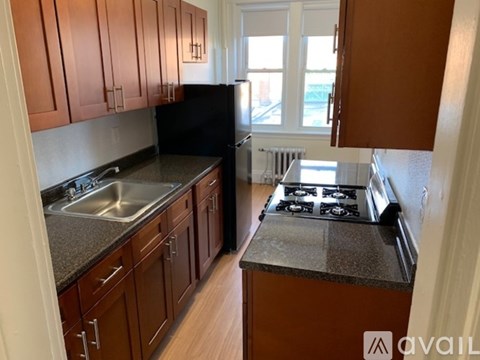 A kitchen with brown cabinets and a black refrigerator.