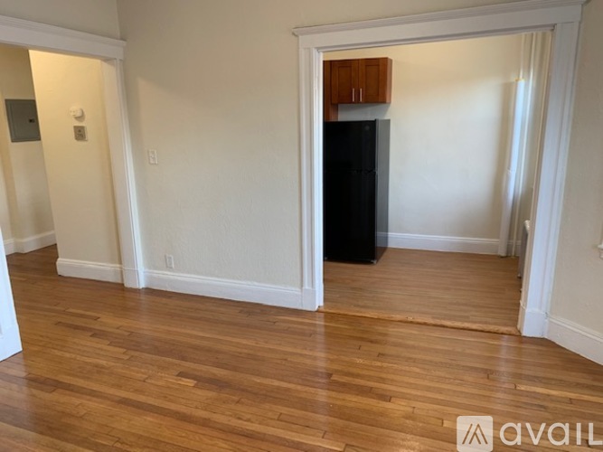 A room with wooden floors and a black refrigerator.