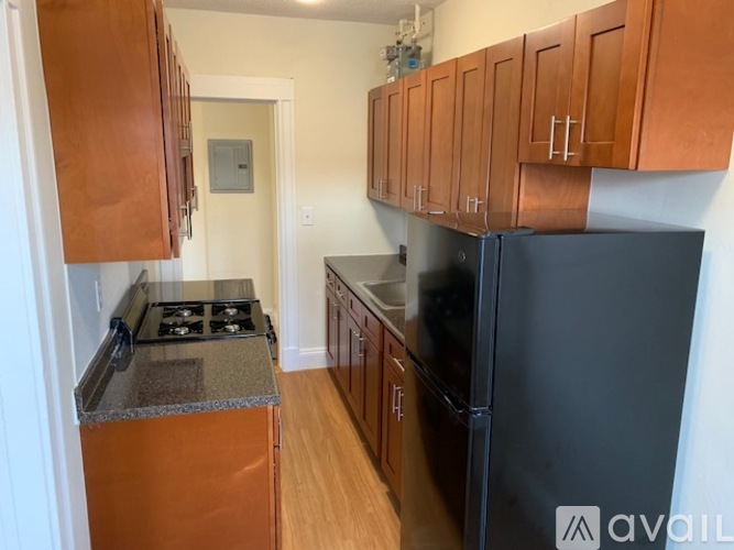 A kitchen with wooden cabinets and a black refrigerator.