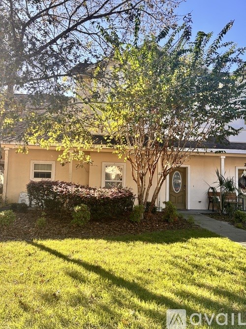 A residential street with houses on both sides and a tree in the foreground.