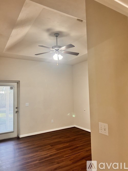 A room with a ceiling fan and wooden flooring.