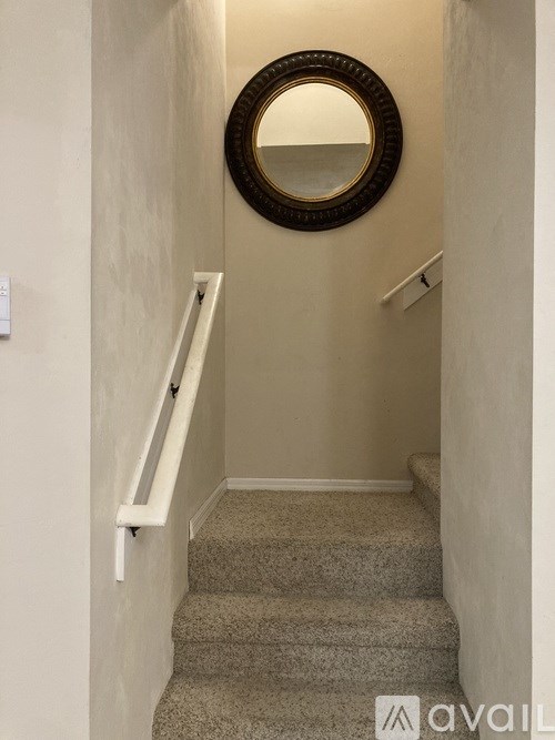 A staircase with a round mirror above it.