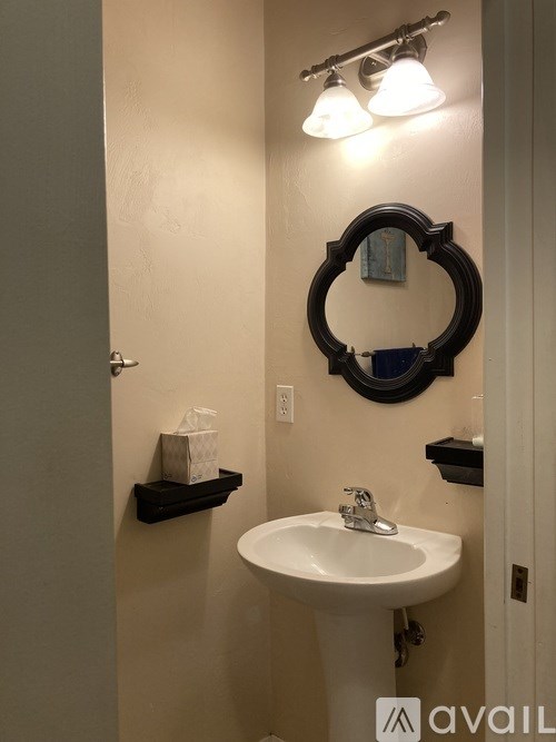 A bathroom with a white sink and a mirror with a black frame.