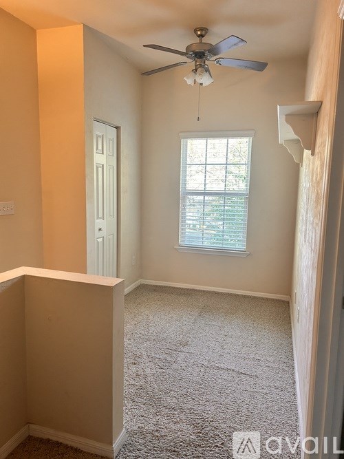 A room with a ceiling fan and a window with blinds.