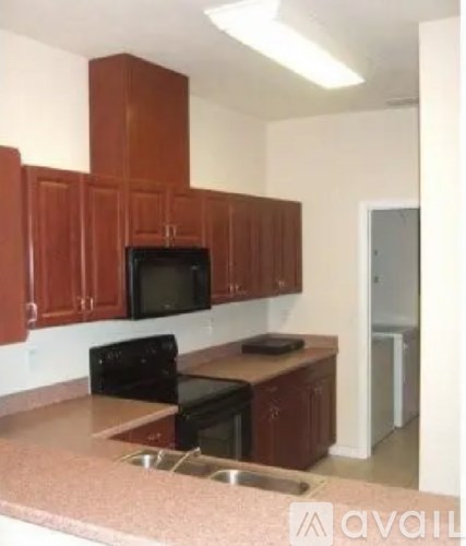 A kitchen with brown cabinets and black appliances.