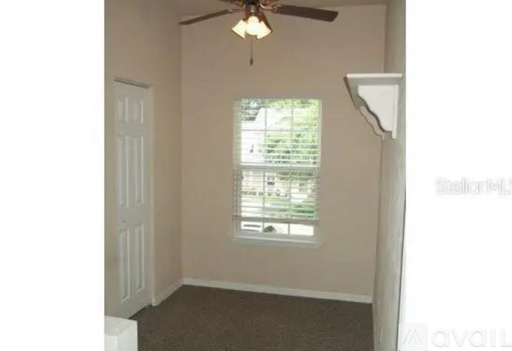 A room with a ceiling fan and a window with blinds.