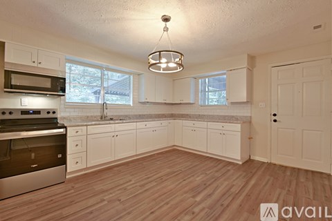 A kitchen with white cabinets and a wooden floor.