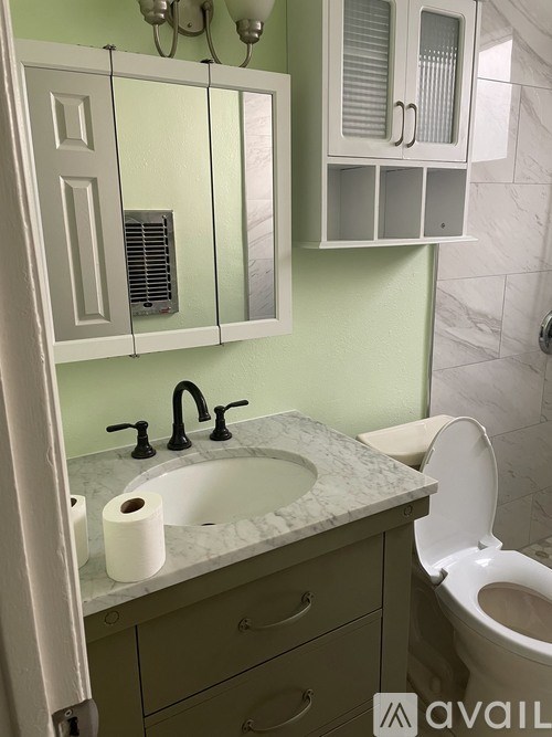 A bathroom with a green wall and a white toilet.