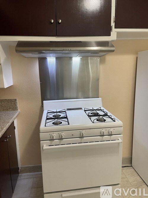 A white gas stove with four burners is in a kitchen.