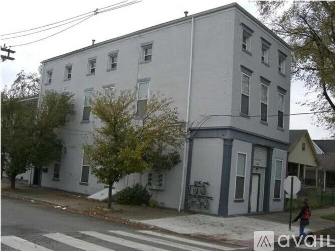 A white building with a blue trim is situated on a street corner.