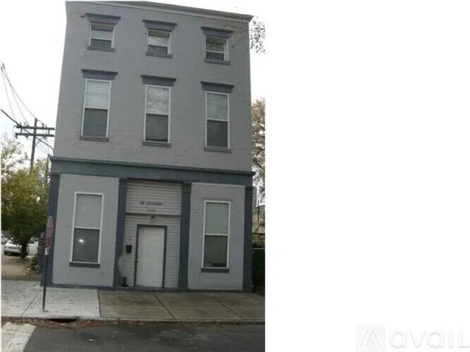 A grey building with a white door and windows.
