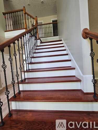 A staircase with a wooden handrail and white risers.