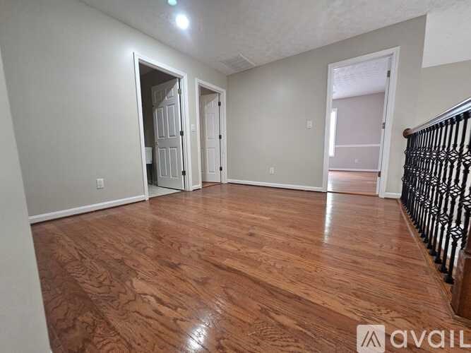 A room with wooden flooring and three doors.