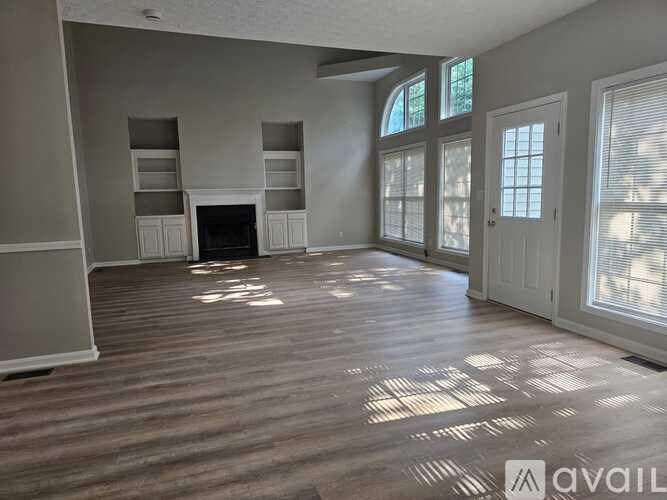 A spacious living room with wood flooring and a fireplace.