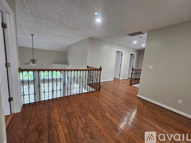 A room with wooden floors and a balcony with a railing.
