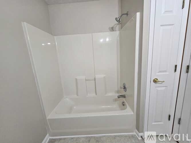 A white bathroom with a bathtub and a door.