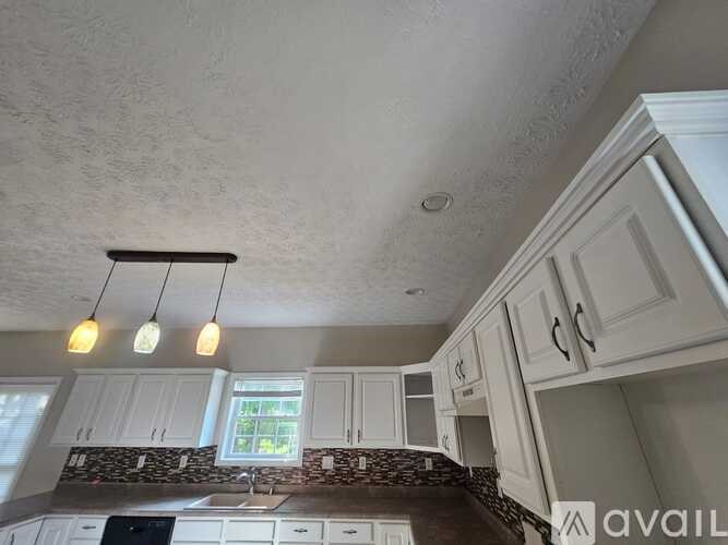A kitchen with white cabinets and a window above the sink.