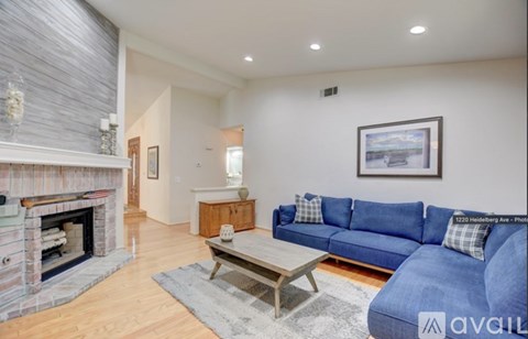 A living room with a blue couch and a fireplace.