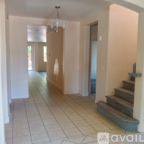 A hallway with a chandelier and a staircase.