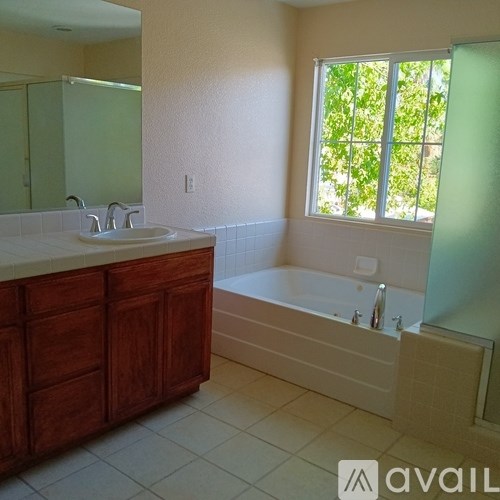 A bathroom with a tub, sink, and window.