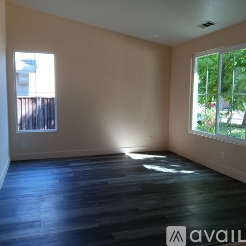 A room with wooden floors and two windows.