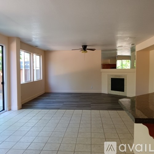 A spacious living room with a fireplace and a ceiling fan.